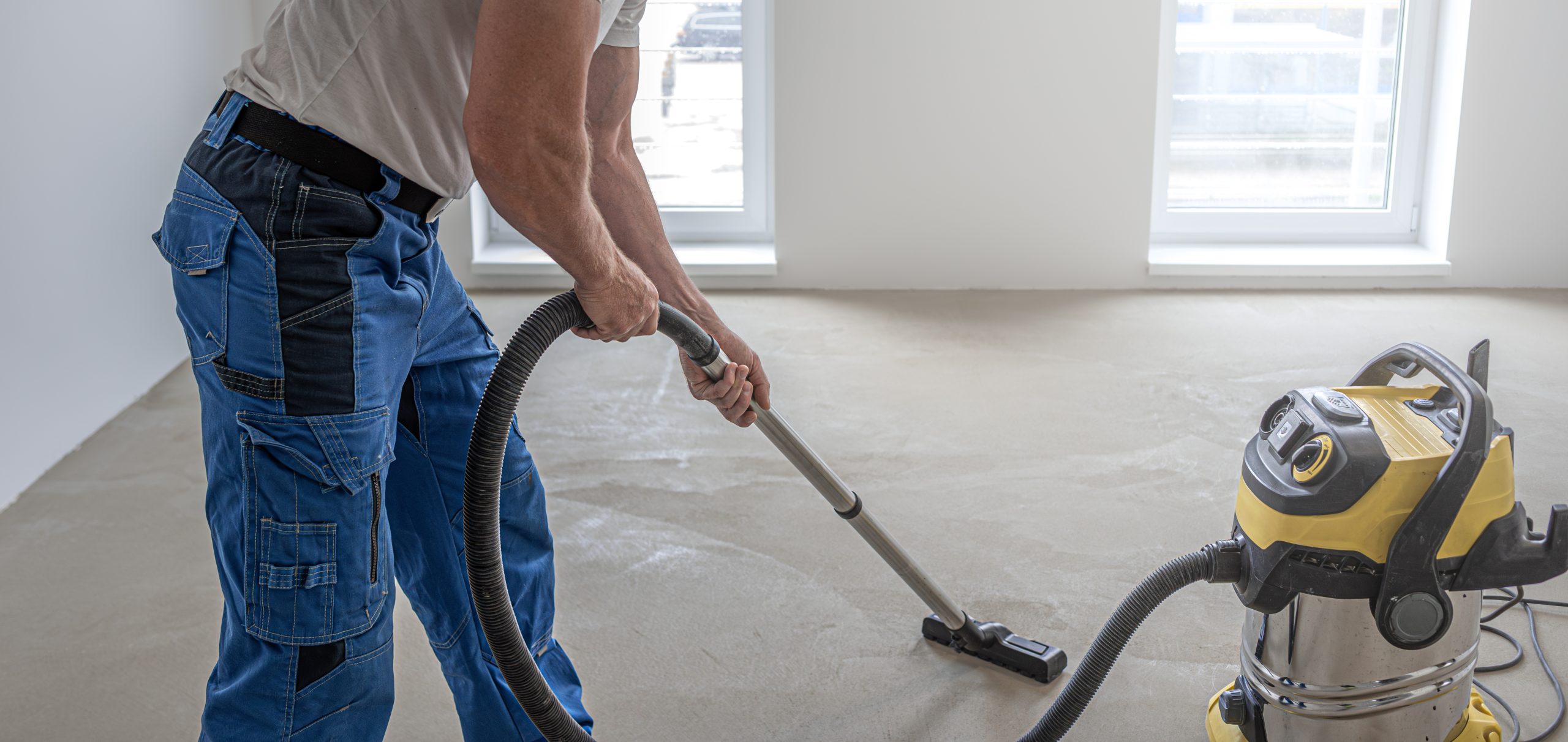 Floating Floor Work. A Worker Vacuums The Floor Before Laying The Vinyl Floor Layer.